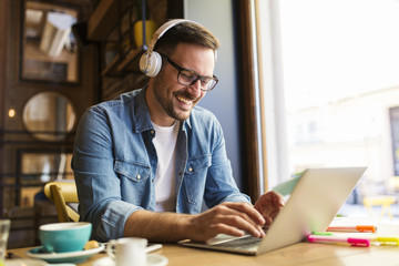smiling man using a lap top in a coffee shop